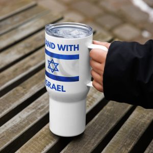 A hand holding a white travel mug with a handle and clear lid. The mug features blue text “I Stand With Israel” and an Israeli flag design, photographed outdoors on a wooden bench.
