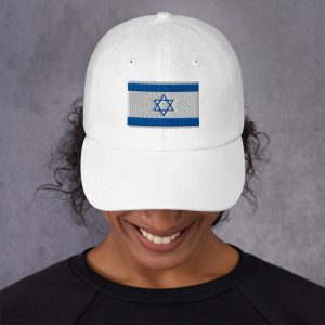A woman wearing a white cap with an embroidered Israeli flag design, looking downward with a smile against a neutral background.