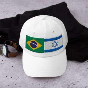 White cap with embroidered Brazil and Israel flags displayed on a flat surface with casual accessories.