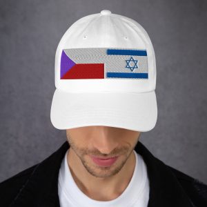 Man wearing a white cap with embroidered Czech Republic and Israel flags, looking downward against a neutral background.