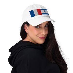 Woman wearing a white cap with embroidered France and Israel flags, looking over her shoulder against a neutral background.