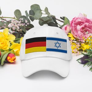 White cap with embroidered Germany and Israel flags, displayed in front of colorful flowers.