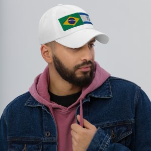 Man wearing a white cap with embroidered Brazil and Israel flags, styled with a casual denim jacket and hoodie.